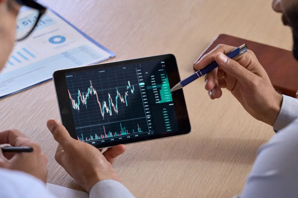 Two people looking at a trading chart on a tablet.